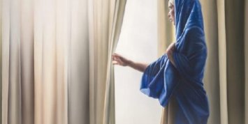 Maria steht am geöffneten Vorhang